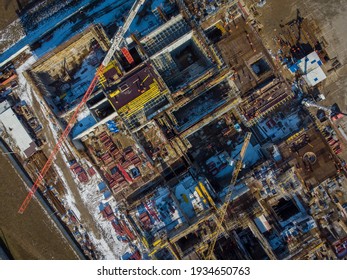 Top view of industrial machinery and building under construction located in enclosure in snowy outskirts