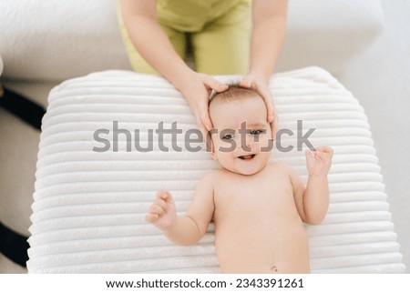 Top view of infant baby boy being manipulated by unrecognizable osteopathic manual therapist or physician. Closeup of female masseuse massage head of small newborn kid. Concept of infant healthcare. [[stock_photo]] © 