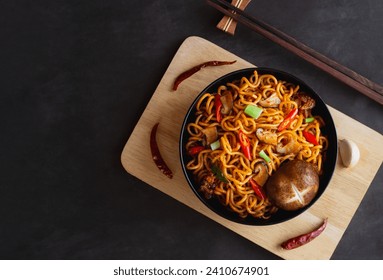 Top view of Instant noodles spicy with chicken, mushroom, white sesame, seaweed sheets and chili in black bowl on black table background. Asia Food - Powered by Shutterstock