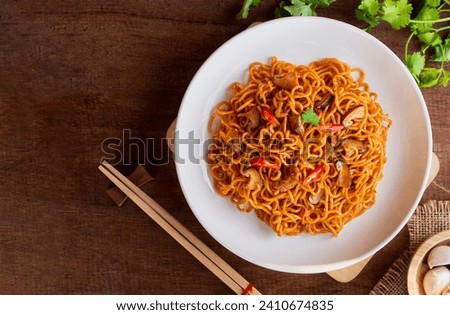 Top view of Instant noodles spicy with chicken, mushroom, white sesame, seaweed sheets and chili in white plate on wooden table background. Asia Food