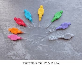 Top view of interdental brushes of different sizes and colors on a gray table.