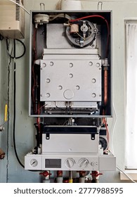 A top view of the internal components of an open gas boiler, clearly showing the copper heat exchanger tubes, ignition system components, and metal combustion chamber housing.