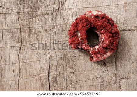 Top view of isolated bite missing red velvet donut or doughnut on wooden table, copyspace