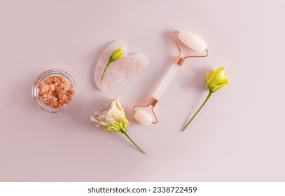 Top view of the items for massage of the face and, neck. rose quartz massager, gua sha scraper, bath salt. Self-care at home. Flat lay