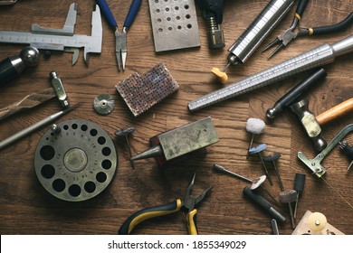 Top View Jewelry Maker Workbench With Tools On Table. Equipment And Tools Of A Goldsmith On Wooden Working Desk Inside A Workshop.