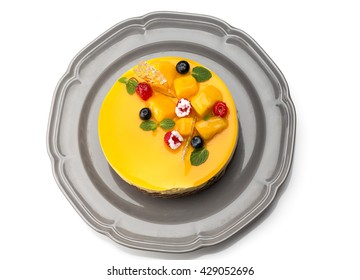 Top view of Joconde Imprime Mango and Passion fruit Mousse Cake, decorated with fresh fruits and berries