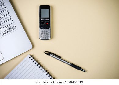 Top view of journalist concept with laptop, blank notebook, pen and digital voice recorder on beige background.