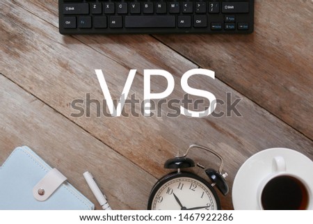 Top view of keyboard,notebook,pen,clock, and a cup of coffee on wooden background written with VPS.