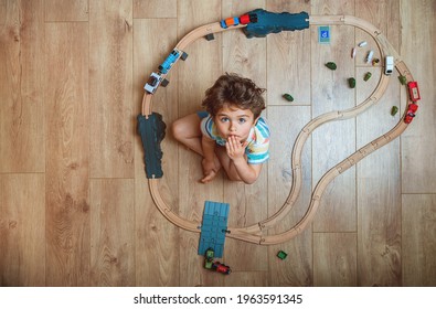 Top View Of Kid Playing Toy Train Railway. Child Sitting On Floor With Wooden Toys. Toys For Little Boy. Preschooler Building Rail Road And Blocks At Home, Daycare. Kindergarten Educational Games