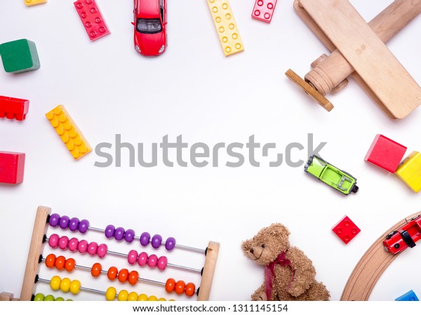 Top view of kids toys\
background. Wooden cubes, colorful toy bricks, scores, plane, train\
on white. Educational toys for preschool, kindergarten or\
daycare.