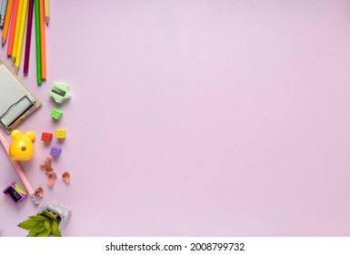 Top View Of Kids Workplace.Pink Desk And Colorful Pencils, Sharpener,decorative Plant,erasers On It.Empty Space