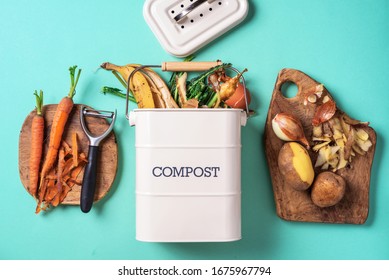 Top view of kitchen food waste collected in recycling compost pot. Peeled vegetables on chopping board, white compost bin on blue background. - Powered by Shutterstock