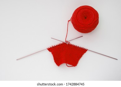 Top view of a knitted pattern of red yarn on an isolated background, copy space. Needlework concept, handmade