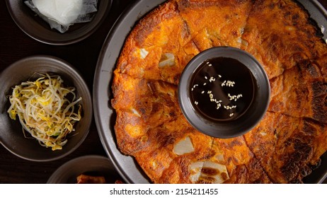 Top view of Korean Grilled BBQ combo sets with kimchi pancake with pancake sauce on the dark plate and black table vibe background