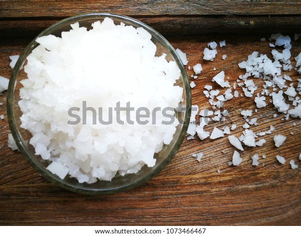 Top view of Kosher salt in a bowl on a wooden table.
