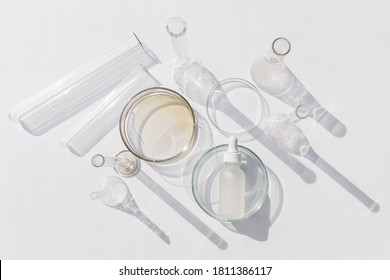 Top View Of Laboratory Glassware And Cosmetic Glass Bottle On Grey Background. Natural Medicine, Cosmetic Research, Bio Science, Organic Skin Care Products.