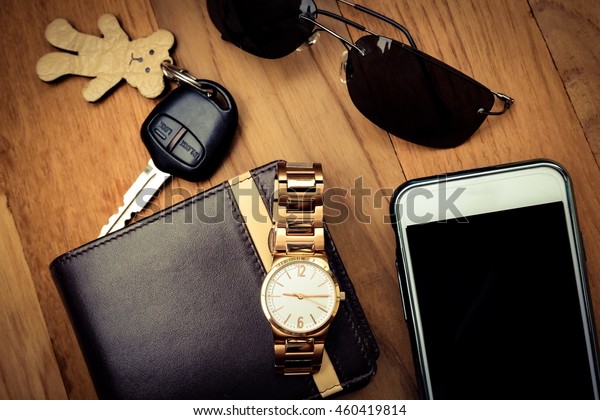 Top view of lady set: watches, car keys,\
sunglasses,and smartphone on\
wooden