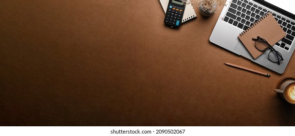 Top view laptop computer, notebook and calculator on brown background. Copy space. - Powered by Shutterstock