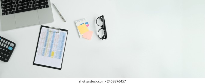 Top view of a laptop computer, a notebook for notes and a calculator on a white table with a place to copy