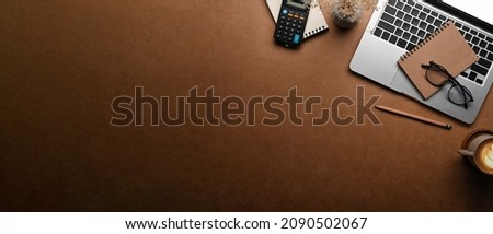 Top view laptop computer, notebook and calculator on brown background. Copy space.