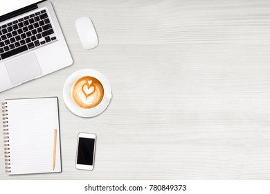 Top view laptop computer or notebook,mobile phone and cup of latte art coffee on wooden table. Business template mock up for adding your text.
