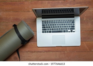 Top View Of Laptop And Gray Yoga Mat In Studio. Sports Concept