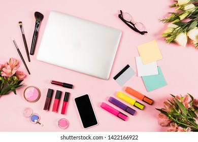 top view of laptop, smartphone with blank screen, credit card, flowers, glasses, highlighters and decorative cosmetics on pink - Powered by Shutterstock