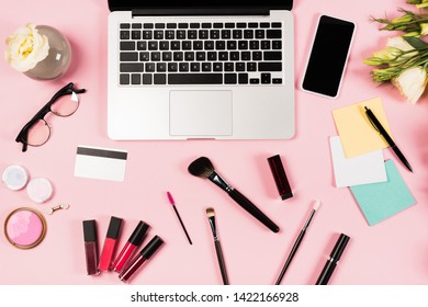 top view of laptop, smartphone with blank screen, credit card, glasses, flowers and decorative cosmetics on pink - Powered by Shutterstock