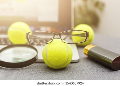 Top View Of Laptop, Sports Equipment, Tennis Ball, Glasses On The Sports Administration White Table.Business Concept.