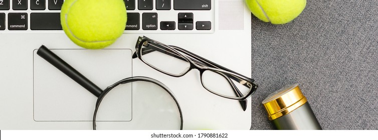 Top View Of Laptop, Sports Equipment, Tennis Ball, Shuttlecock, Glasses Aon The Sports Administration Gray Table.Business Concept.