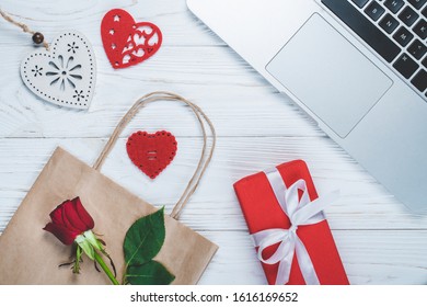 Top View Of Laptop And St. Valentine's Day Or Mother's Day Decorations, Paper Gift Bag And Rose Flowers.  Flatlay Background. Online Shopping, Holiday Sale Concept.