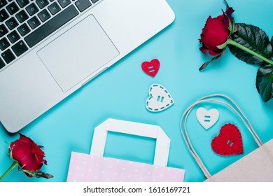 Top View Of Laptop And St. Valentine's Day Decorations, Paper Gift Bag And Rose Flowers.  Flatlay Background. Online Shopping, Holiday Sale Concept.