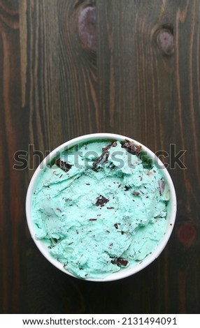 Top View of a Large Cup of Mint Chocolate Chip Ice Cream on Dark Brown Wooden Backdrop