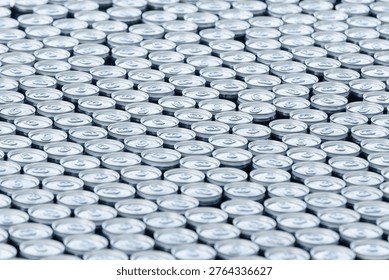 Top view of a large stack of aluminum beer cans arranged in rows, creating a repetitive metallic pattern. Concept of beverage production, brewery industry, packaging and mass manufacturing.