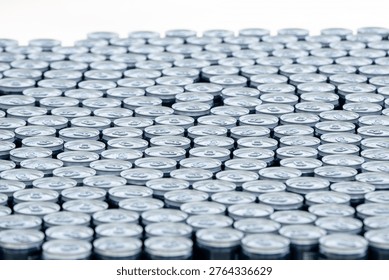 Top view of a large stack of aluminum beer cans arranged in rows, creating a repetitive metallic pattern. Concept of beverage production, brewery industry, packaging and mass manufacturing.