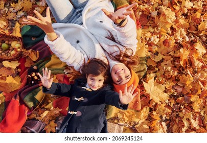 Top View. Laying Down On The Ground. Mother With Her Little Daughter Is Having Walk In The Autumn Park.