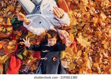 Top View. Laying Down On The Ground. Mother With Her Little Daughter Is Having Walk In The Autumn Park.