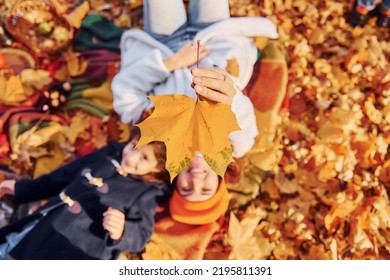 Top View. Laying Down On The Ground. Mother With Her Little Daughter Is Having Walk In The Autumn Park.