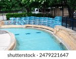 Top view lazy river full stack of clear floats transparent bathing swimming rings near metal fence entrance of upscale hotel resort waterpark in Grapevine, Texas, limestone wall overflow drainage. USA