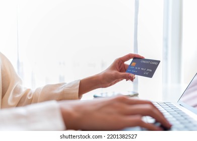 Top View Left Hand Of Asian Woman Holding Credit Card And Input Credit Card Number To Laptop For Purchase Shopping Online, Finance Concept.