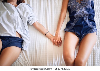 Top View Of Lesbians Holding Hands, Lying On Bed. Lesbian, Couple, Romance Concept