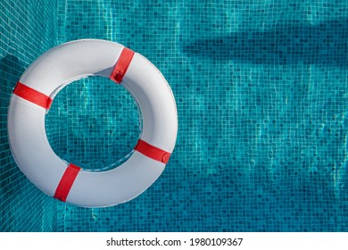 Top view of lifebuoy floating on top of sunny blue water in the swimming pool