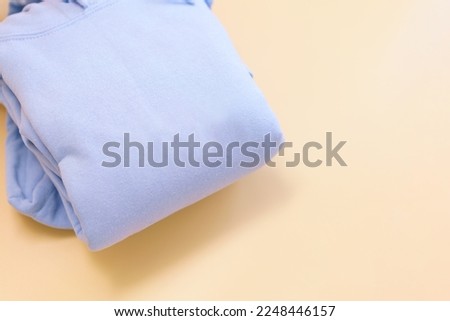 A top view of a light blue cotton folded hoody sweatshirt lays down on an orange background. Fashion. Blank. Clothing. Design. Apparel.  Textile. Wear. Hood. Casual