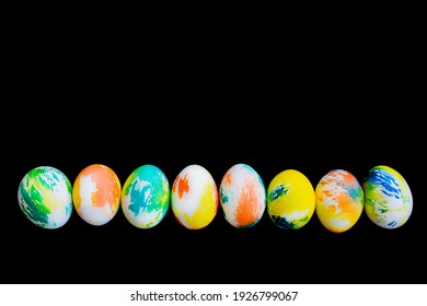 Top view a line of multicolored eggs on a black isolated background. Happy Easter card. Dyed Easter eggs. Copy space for your text. Flat lay style. Top view. 
