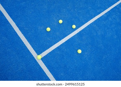 Top view of a line and texture of blue paddle tennis court and five yellow balls. Artificial grass paddle court ground. - Powered by Shutterstock