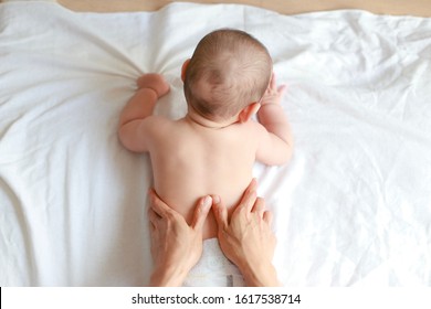 Top view of little baby massaging back by his mother at home. Newborn boy relaxing time after bathing.