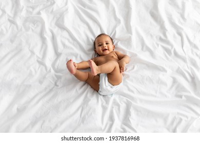 Top view of little black baby lying on bed at home