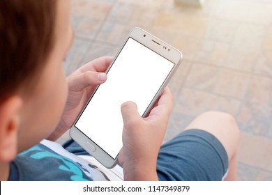 Top View Of Little Boy Holding Phone With Empty White Screen. Kid Play Game, Surfing Online, Learning...etc. Mockup