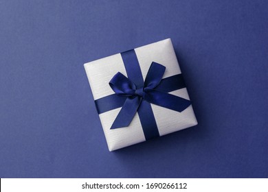 Top view of a little gift box with ribbon. Blue backdrop with space for your text