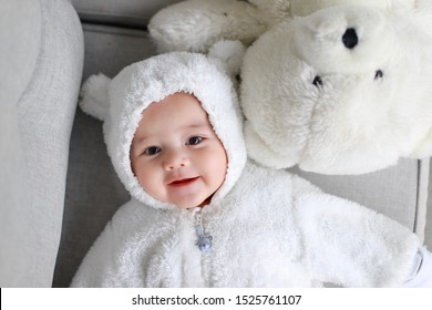 Top view of little infant baby boy wearing teddy bear costume lying next to white polar bear. Happy Asian-German kid 4-5 months old